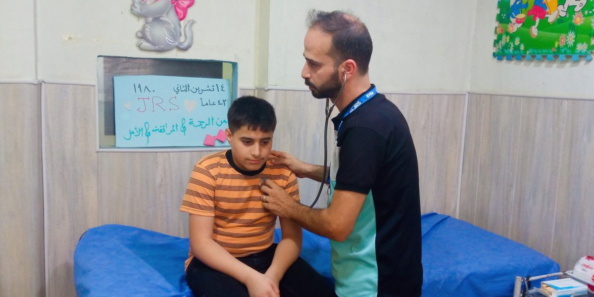 JRS doctor providing medical care to a child in Aleppo